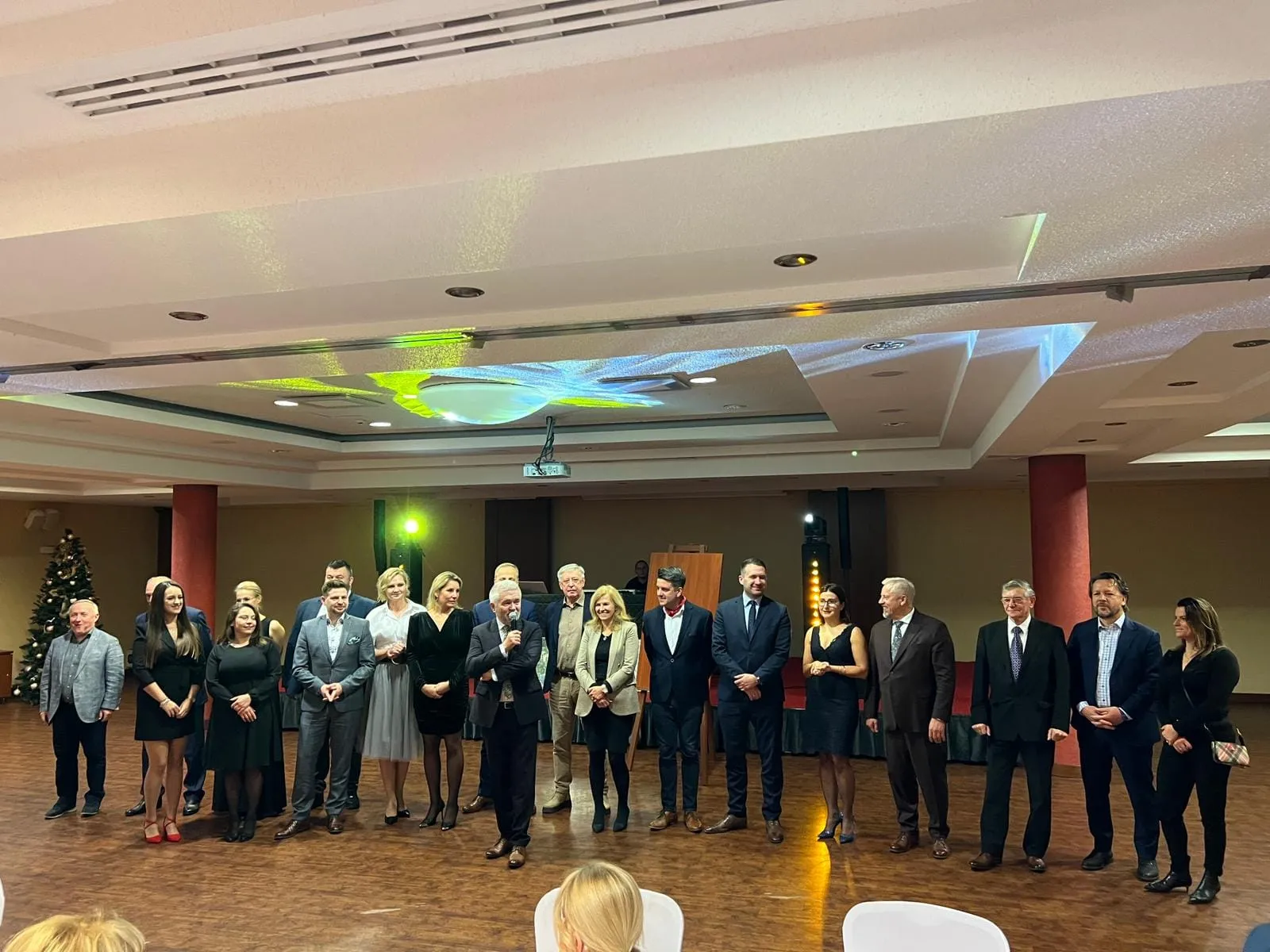 Grupa uczestników I Zjazdu Szkoleniowo‑Integracyjnego Izby Branży Komunalnej stoi w rzędzie na sali konferencyjnej podczas oficjalnej części wydarzenia.