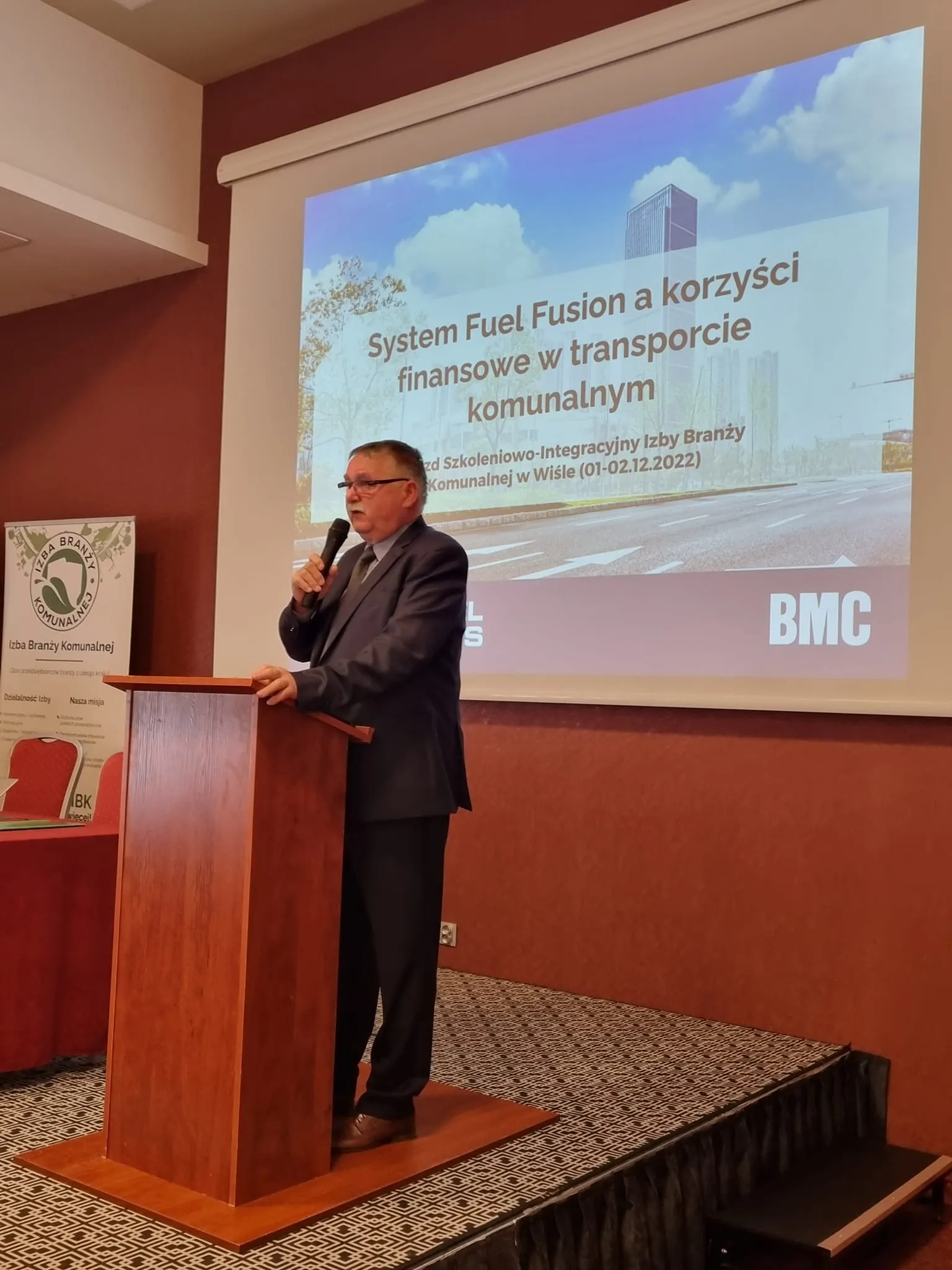 Mężczyzna przemawia przy mównicy podczas prezentacji „System Fuel Fusion a korzyści finansowe w transporcie komunalnym” na I Zjeździe Szkoleniowo-Integracyjnym Izby Branży Komunalnej.