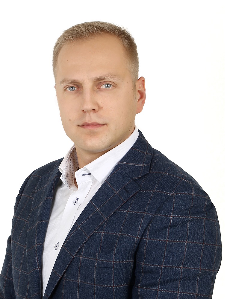 Portret mężczyzny w garniturze w kratę na białym tle, oficjalne zdjęcie przedstawiciela władz.