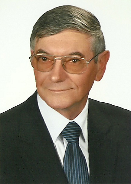Portret starszego mężczyzny w garniturze i krawacie, na jasnym tle, w ujęciu oficjalnym.